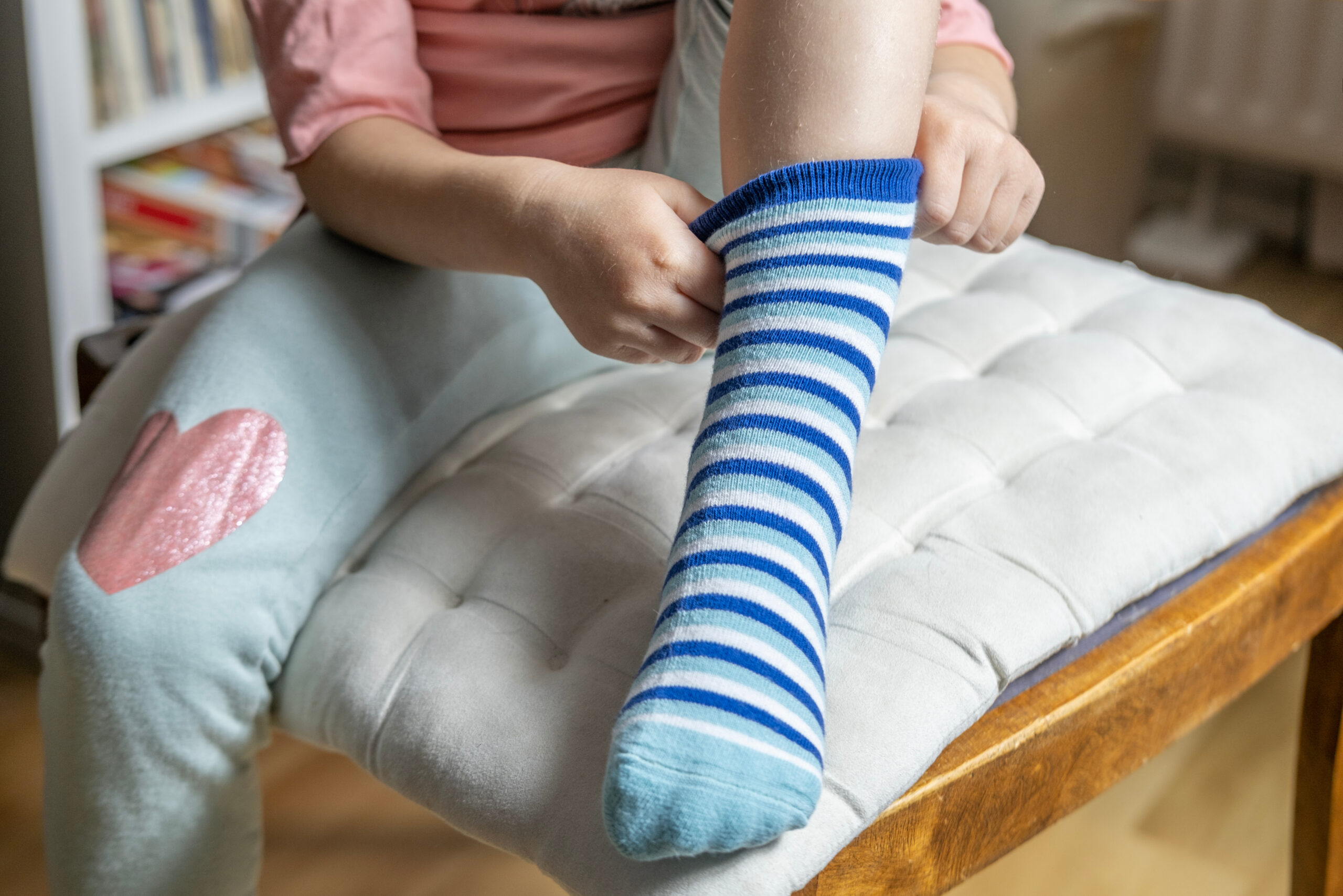 close-up of female 4-year-old child, Preschooler learning to dress independently, putting on blue striped sock, Young kid achieving self-dressing milestones, Fine motor development, Self-care skills girl brushing her teeth