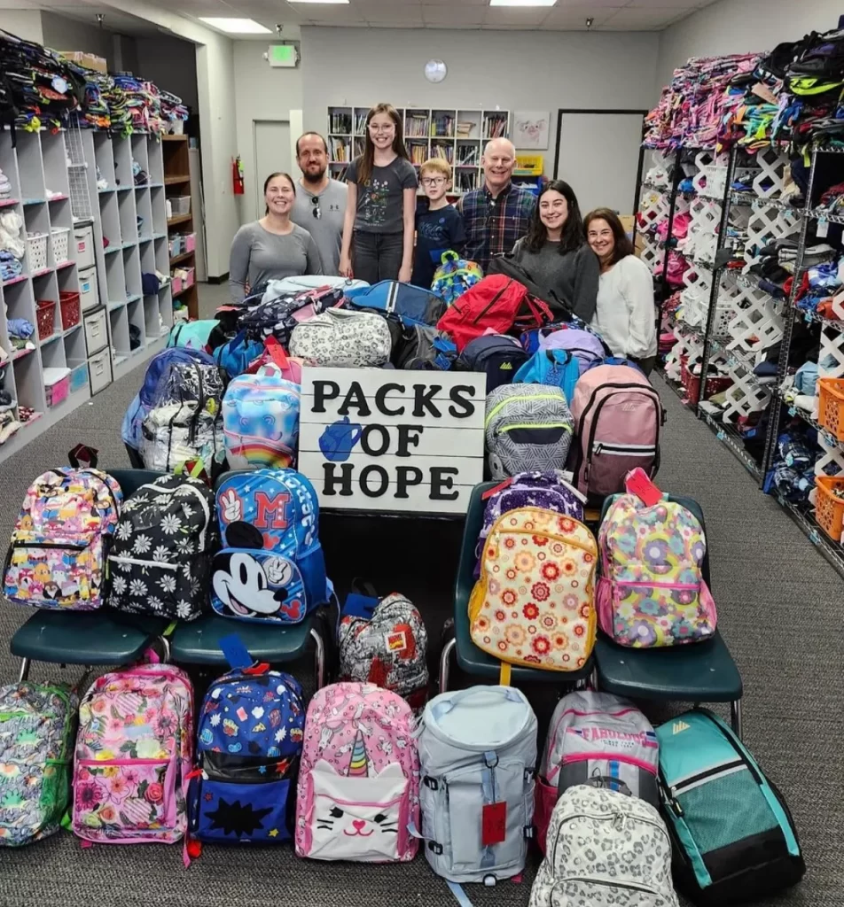 Volunteers of Packs of Hope with donated backpacks and Packs of Hope sign